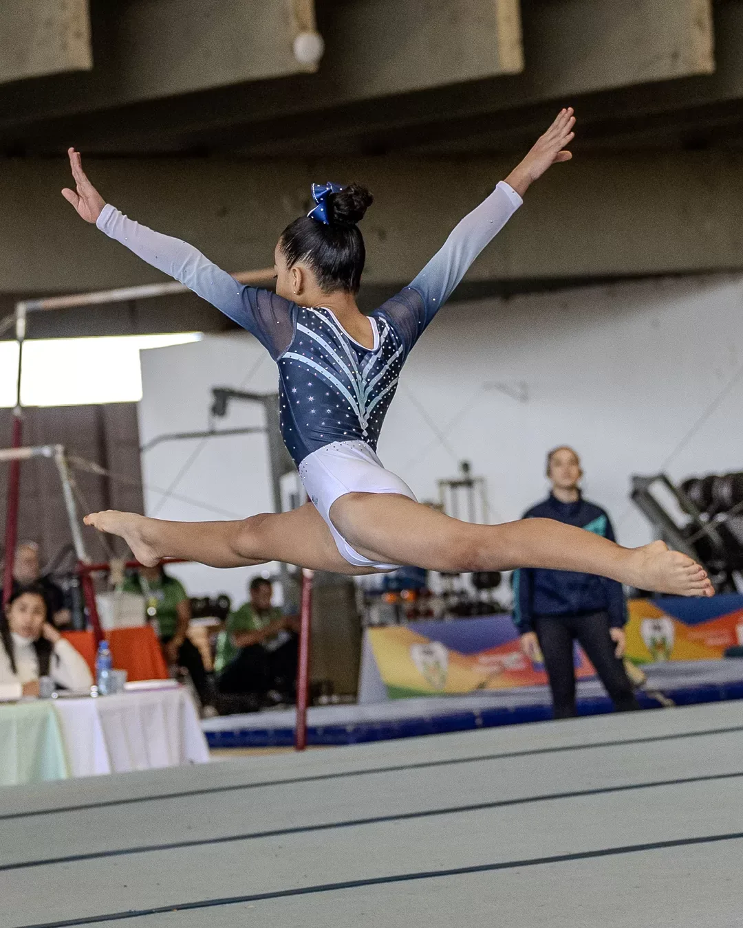 Ginasta em salto com as pernas em afastamento