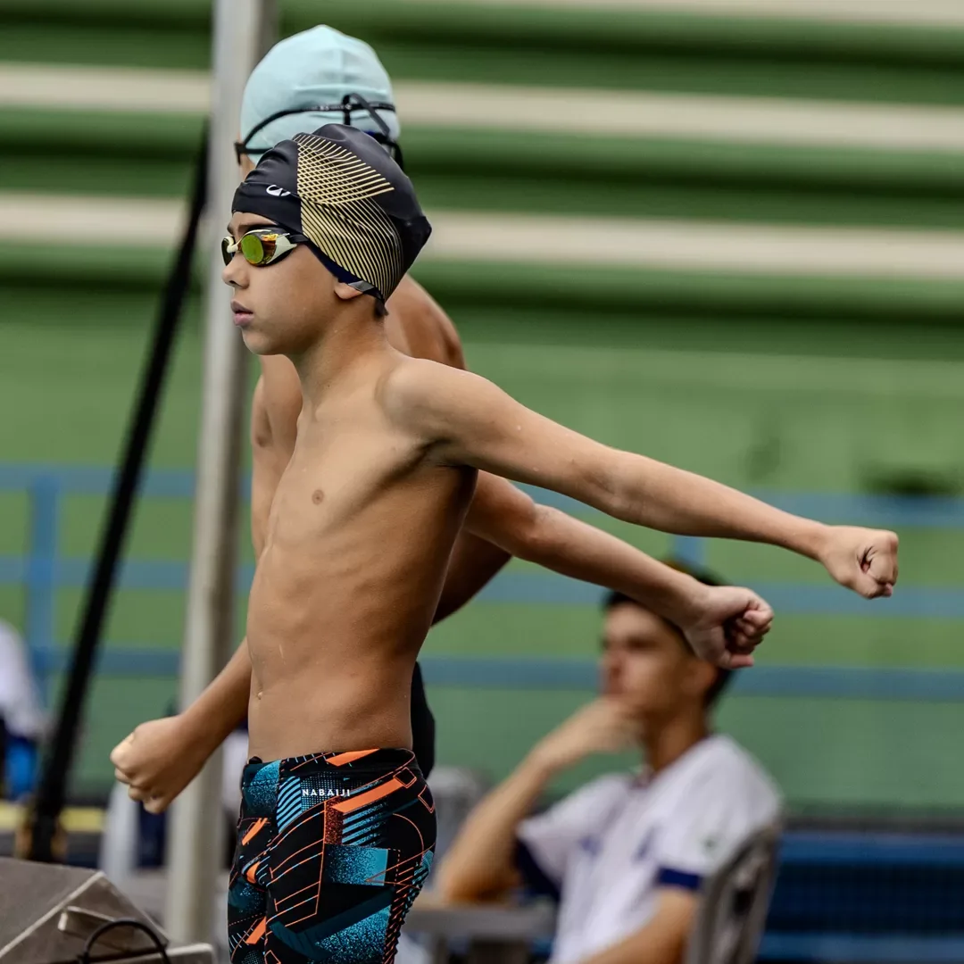 Nadador jovem alongando o braço à beira da piscina