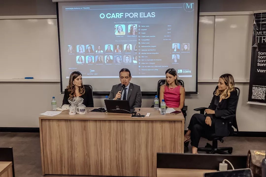 Mesa de debate diante do telão do evento