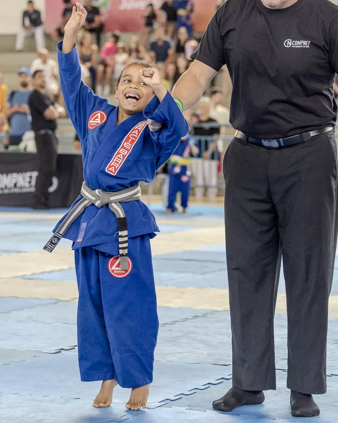 Atleta de kimono azul com o braço erguido ao fim da luta