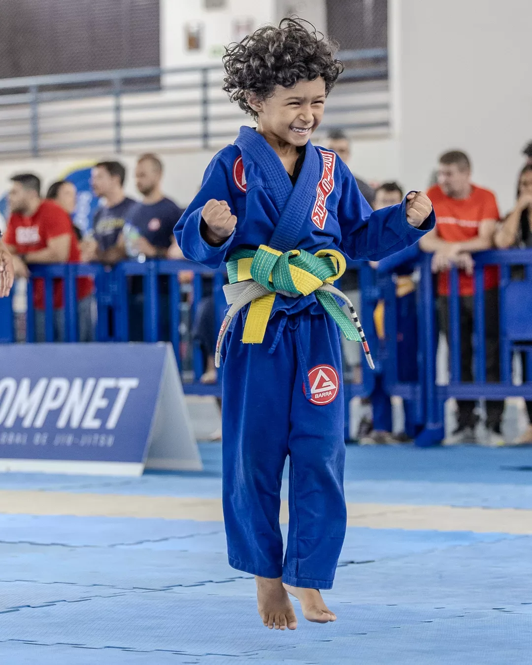 Criança de kimono azul comemorando a vitória no tatame