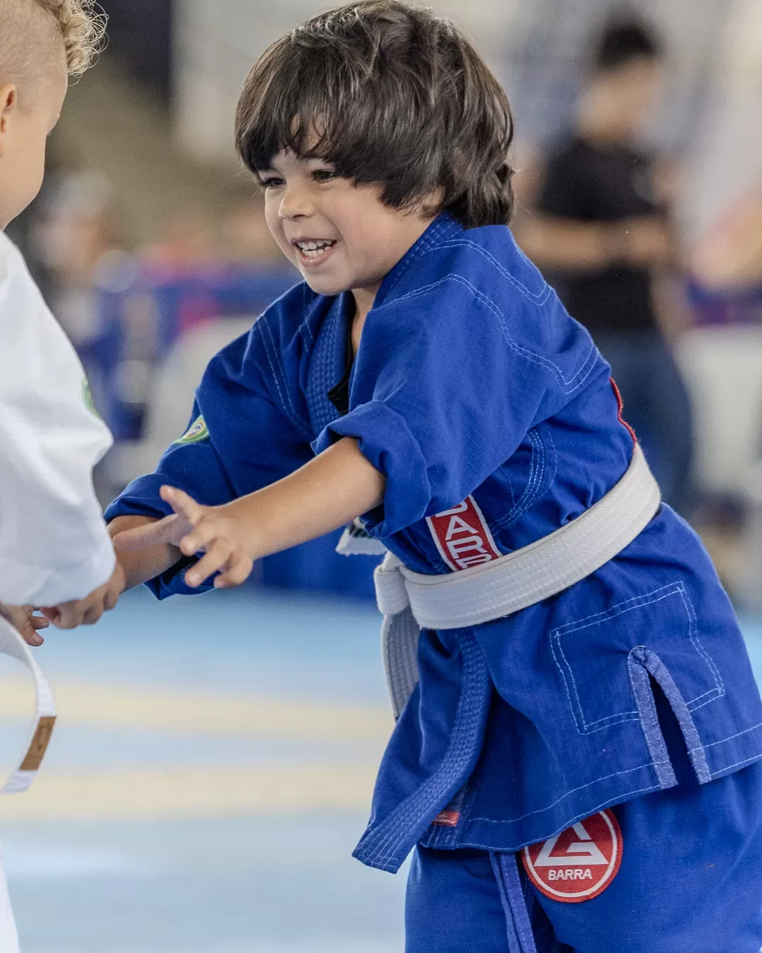 Criança de kimono azul sorrindo no tatame