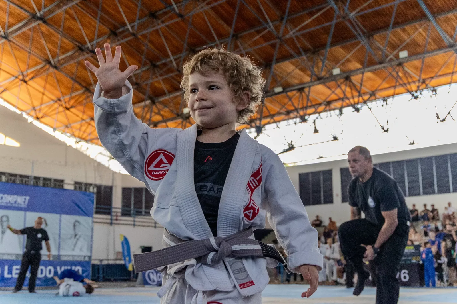 Criança de kimono levanta a mão ao fim da luta