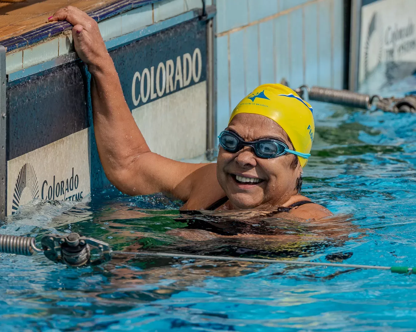 Nadadora sorrindo apoiada na borda da piscina