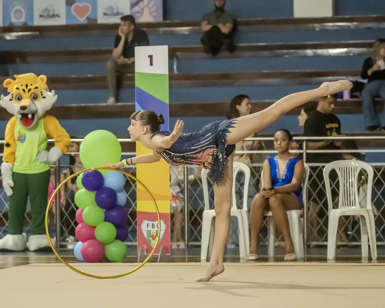 Ginasta em série com o arco na área de premiação