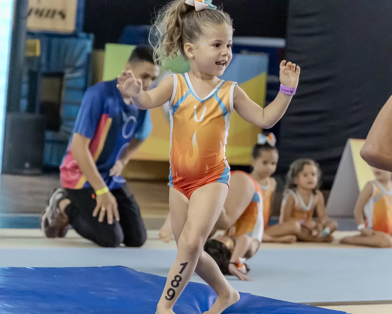 Ginasta pequena sorrindo ao entrar no praticável