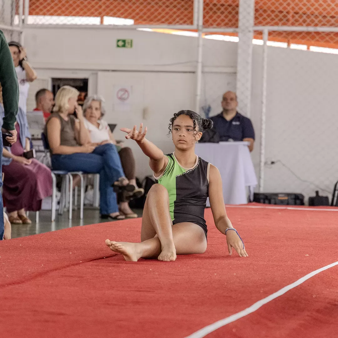 Ginasta sentada no praticável ao encerrar a série