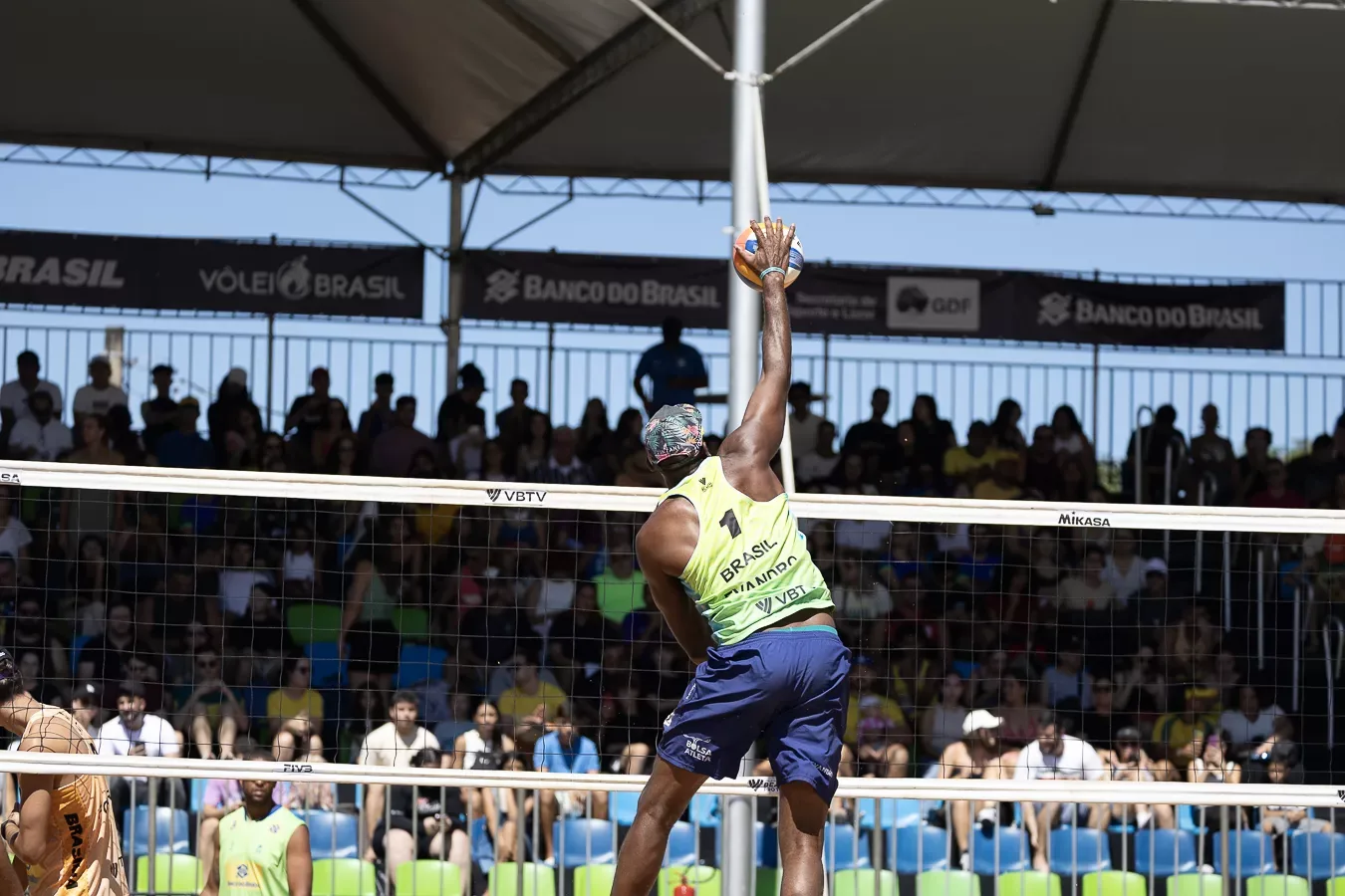 Atleta salta para atacar diante da arquibancada cheia