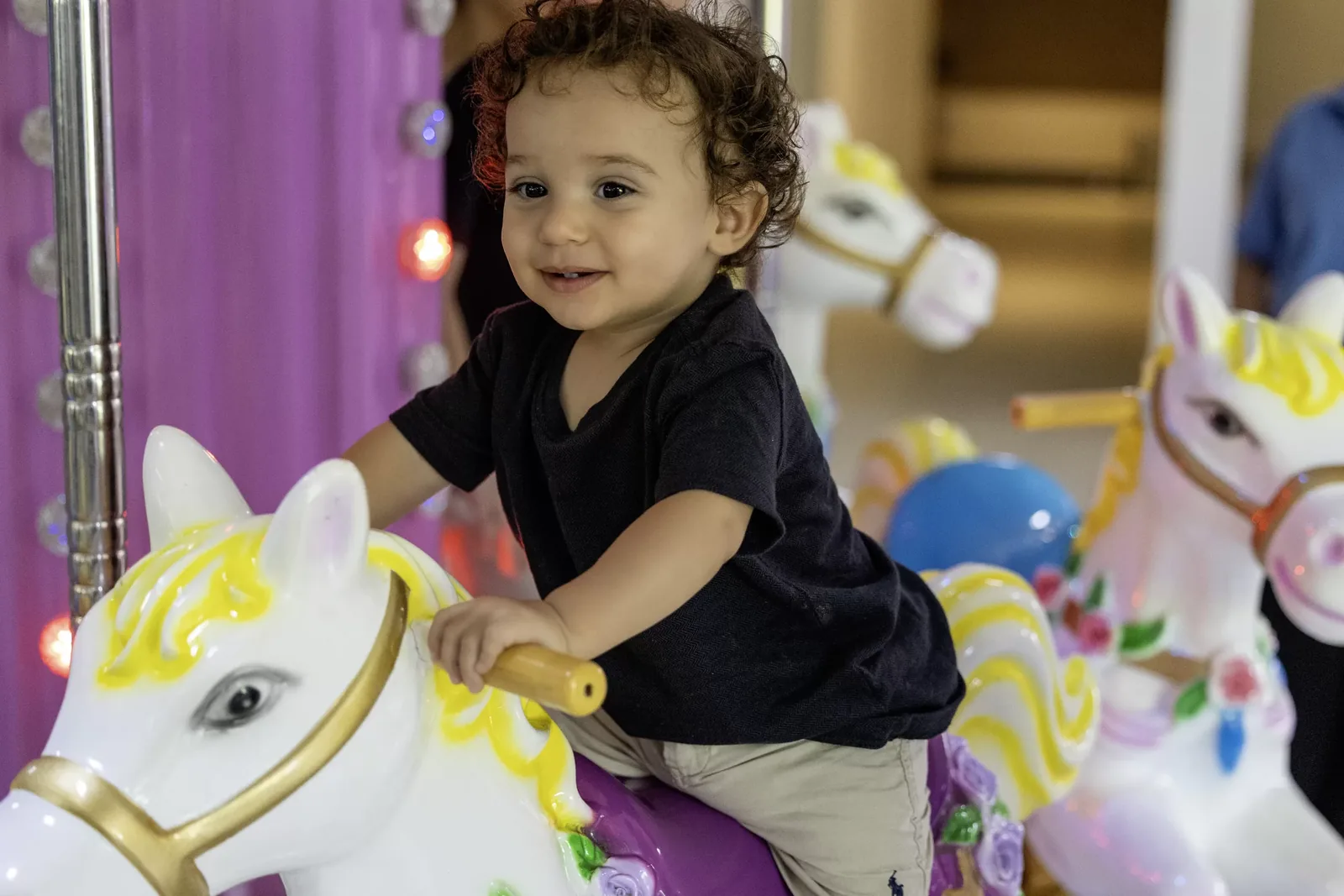 Criança pequena sorrindo no cavalinho do carrossel