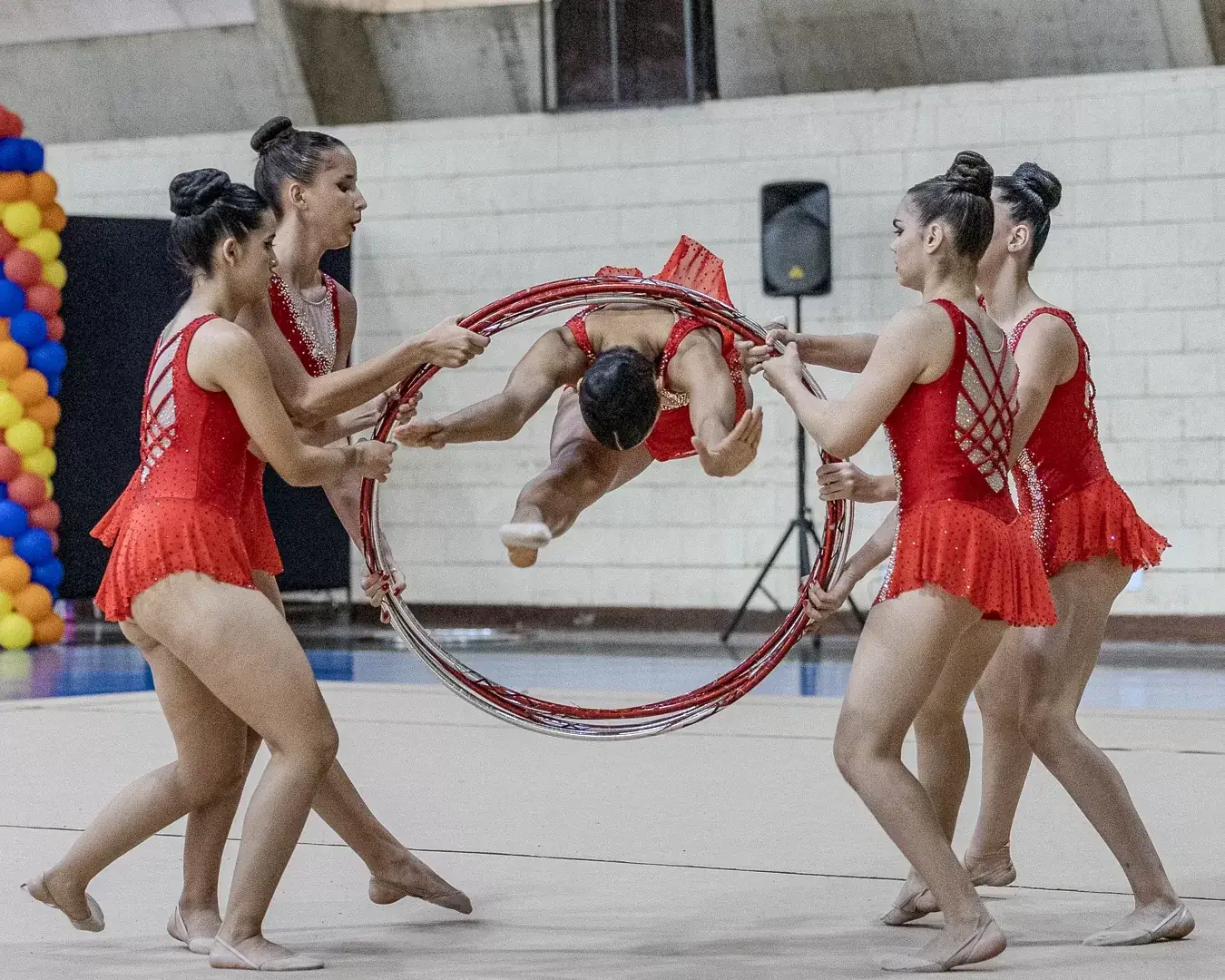 Ginastas em movimento passando pelo arco durante a série de conjunto