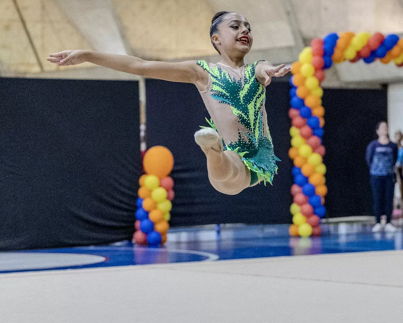 Ginasta em salto com as pernas estendidas no ar