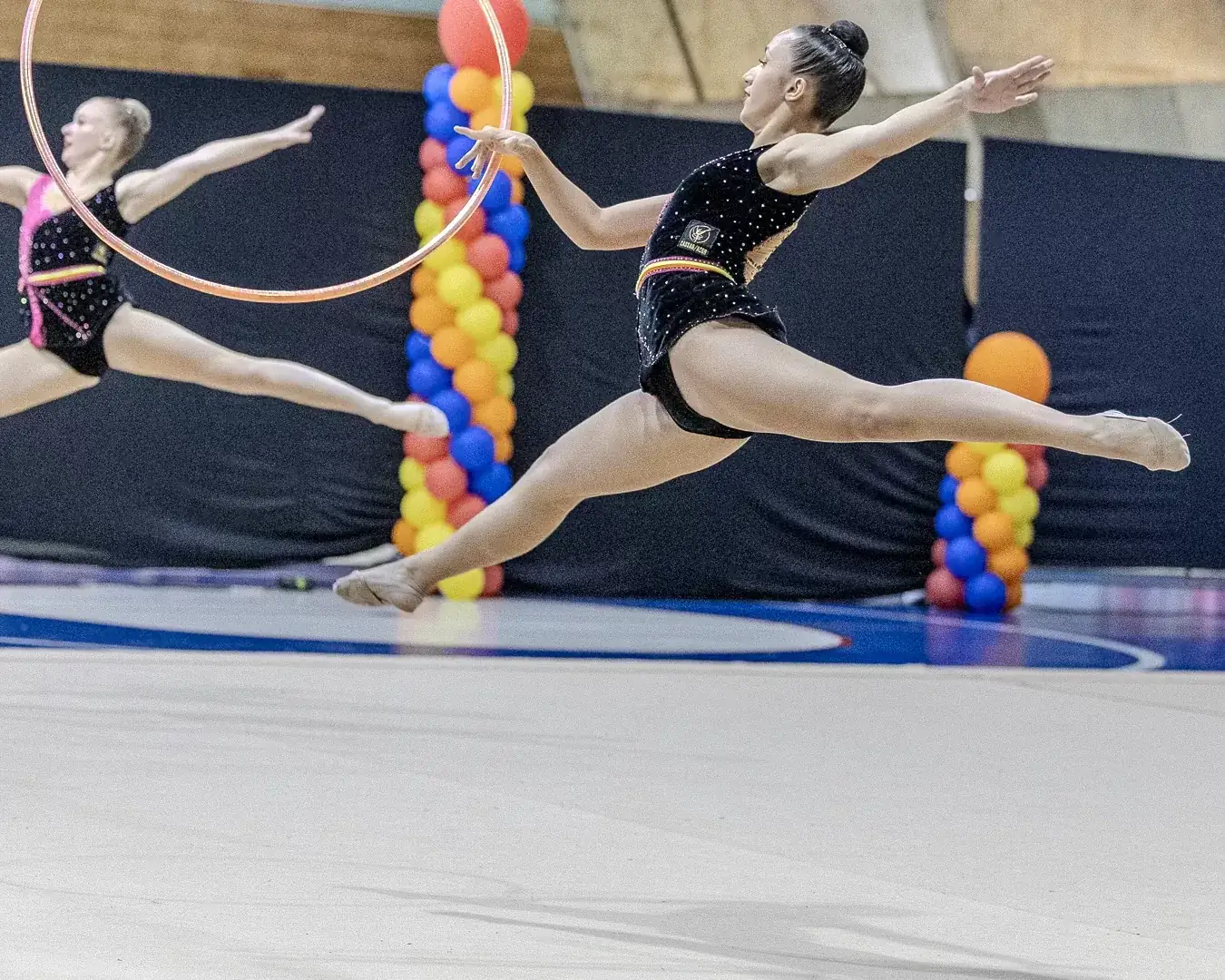 Duas ginastas em salto simultâneo com o arco