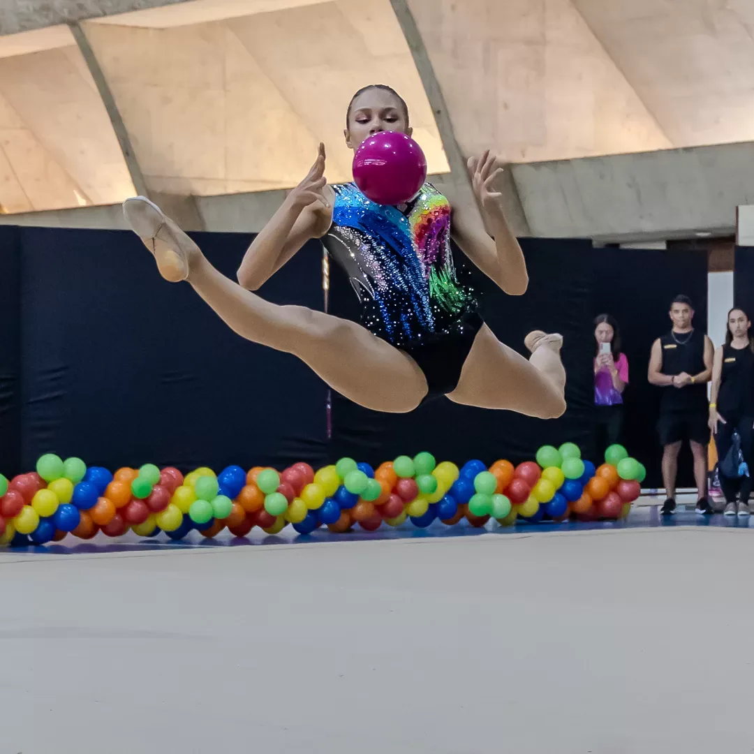 Ginasta em salto com a bola no alto