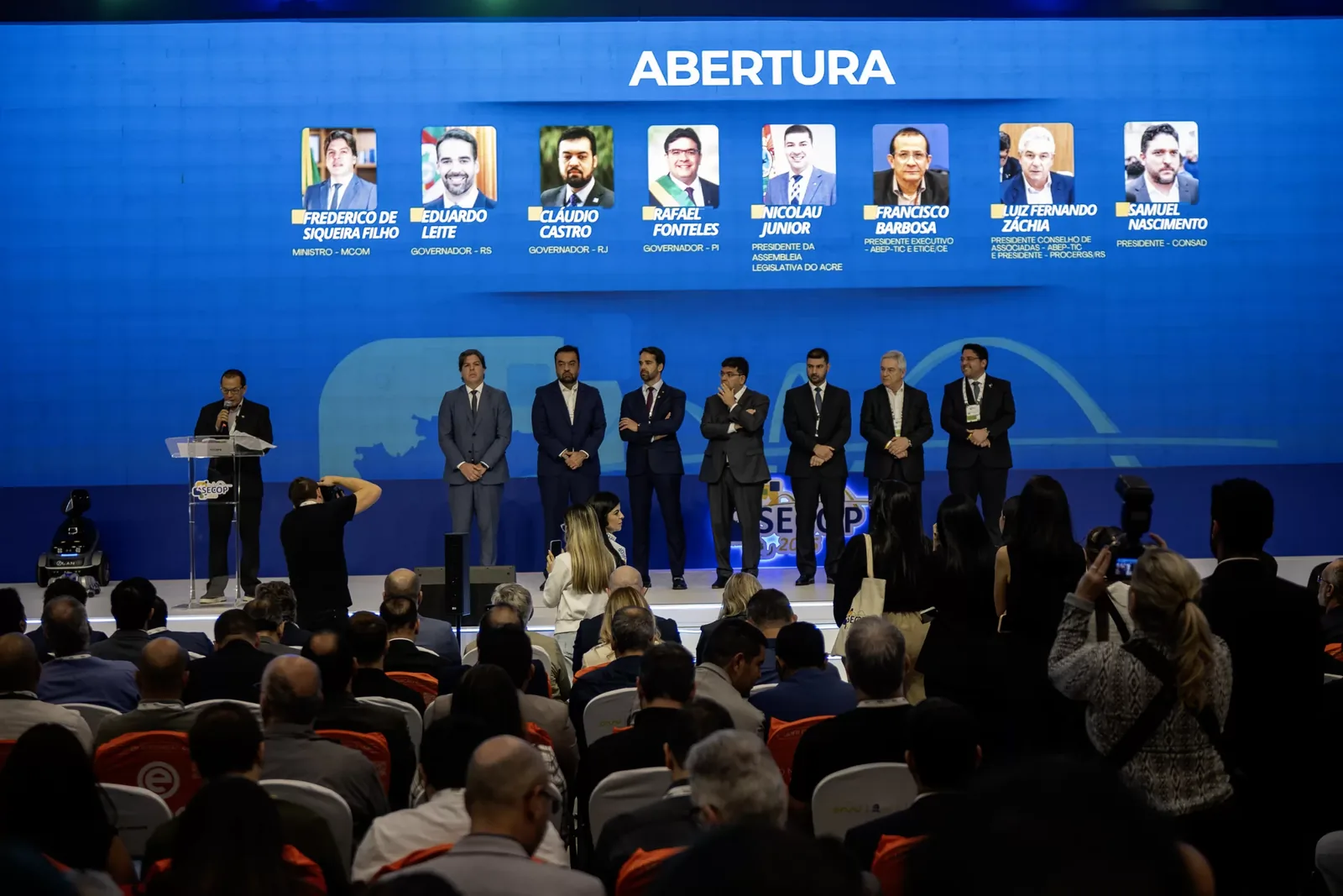 Cerimônia de abertura no palco, diante do auditório cheio