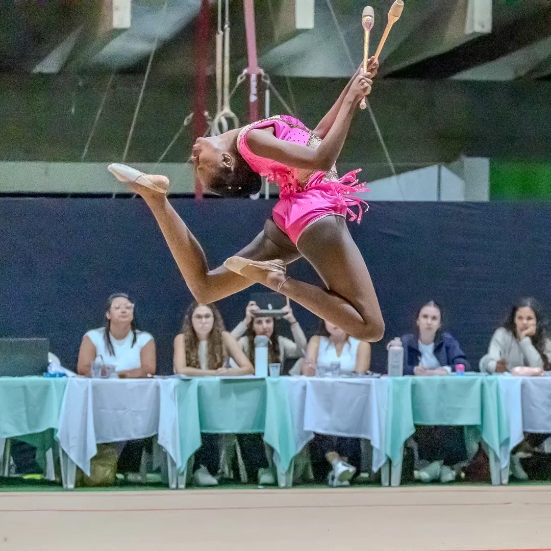 Ginasta em salto com as maças no alto