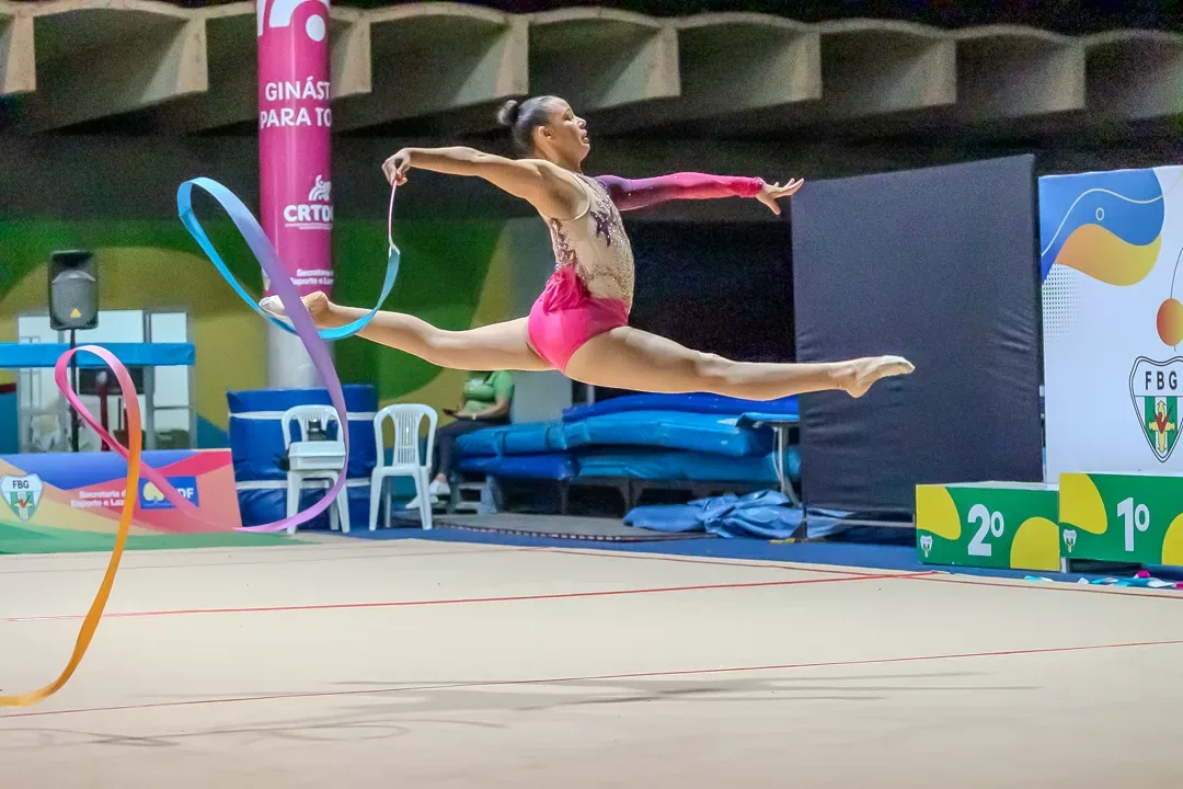Ginasta em salto com a fita no praticável