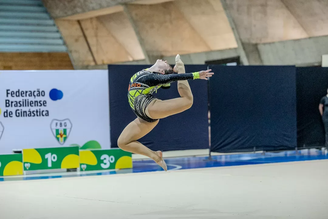 Ginasta em salto com as pernas recolhidas