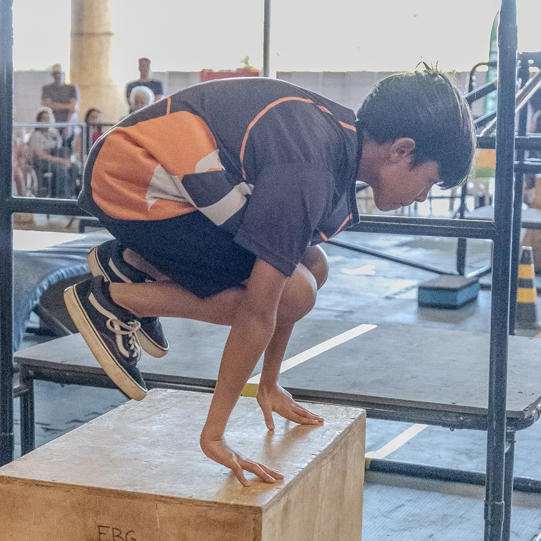 Atleta pousando agachado no caixote com as mãos apoiadas