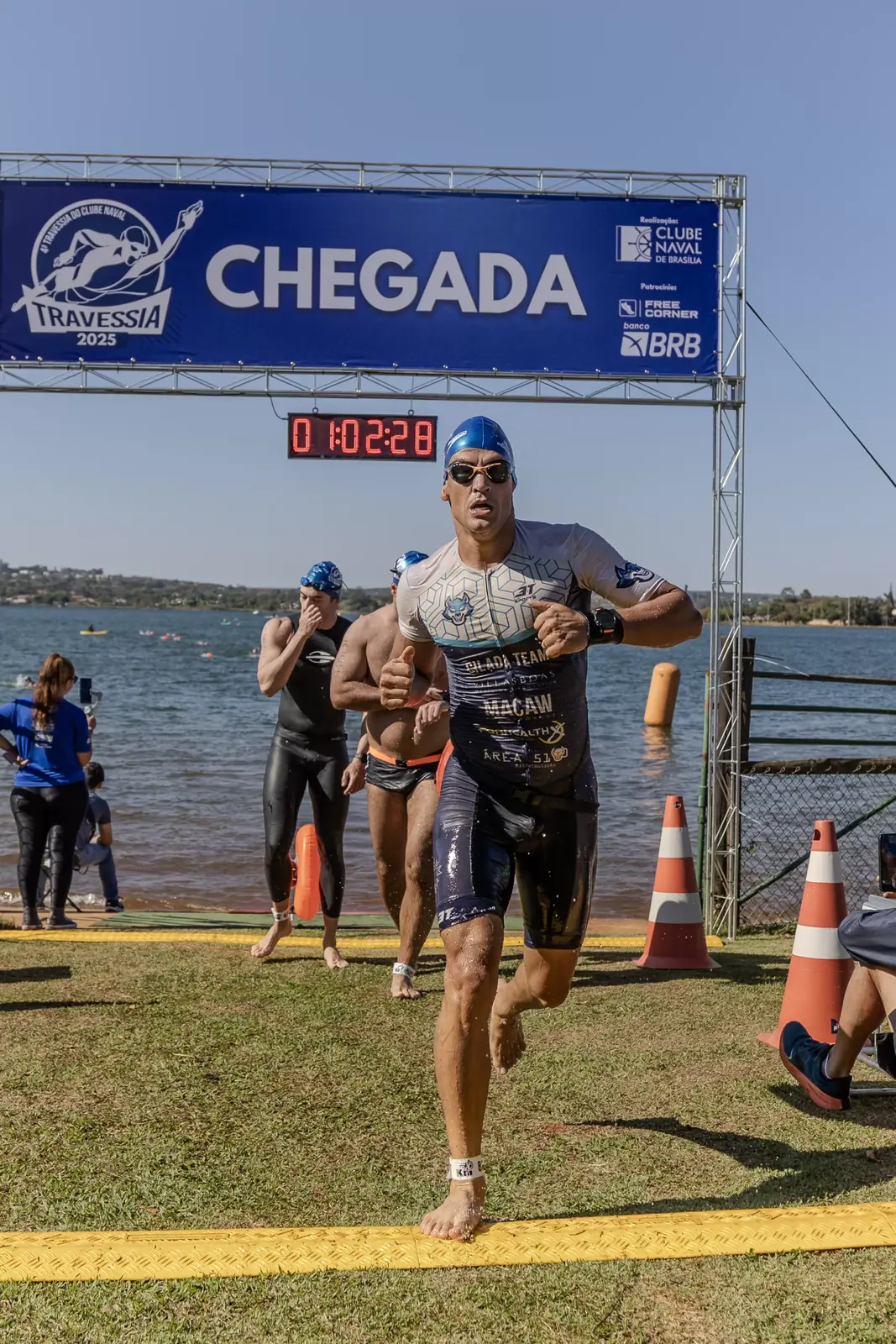 Atleta cruzando o pórtico de chegada com o cronômetro ao fundo