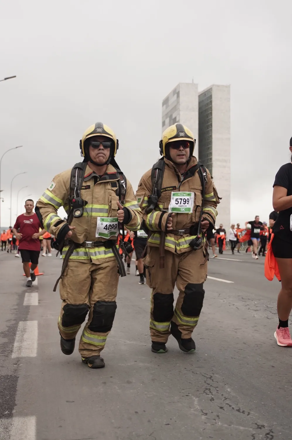 Bombeiros correndo em traje de operação com o Congresso ao fundo