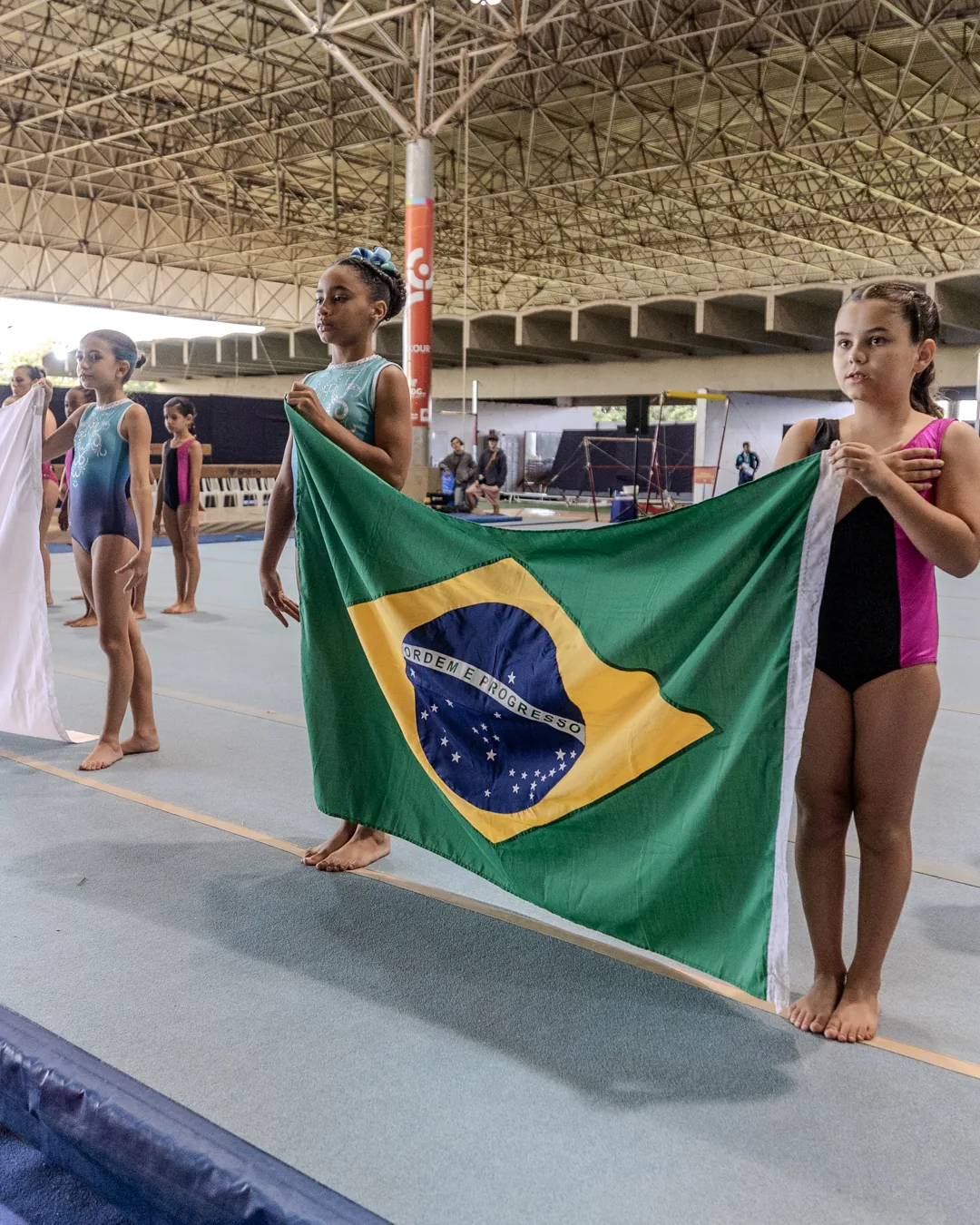 Ginasta segurando a bandeira do Brasil na abertura do torneio