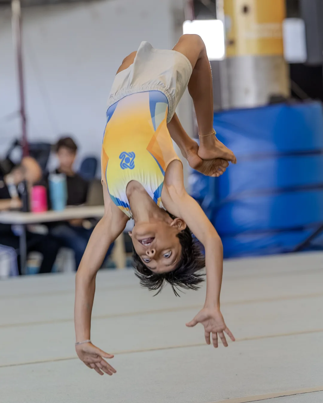 Ginasta em salto acrobático invertido, sorrindo