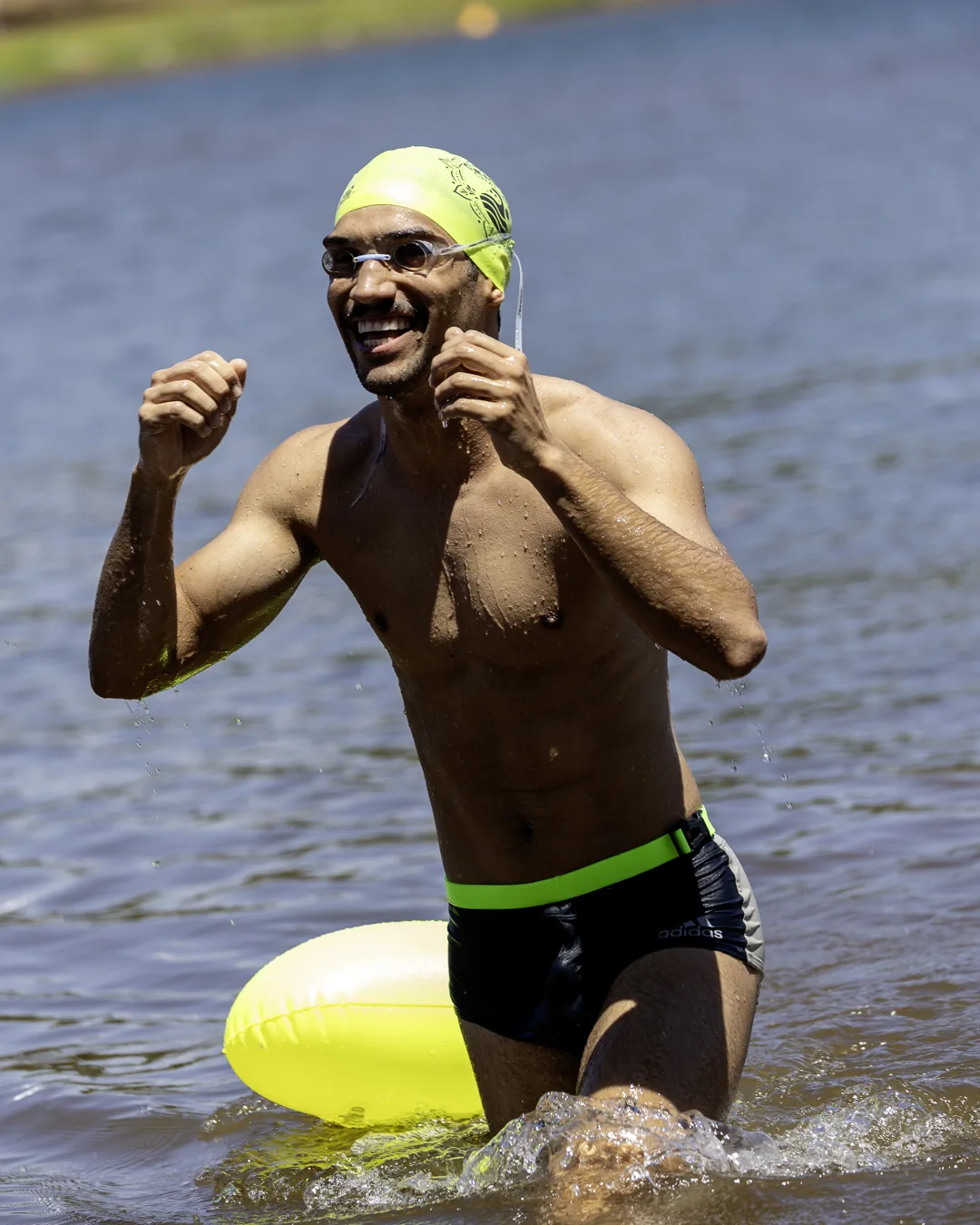 Nadador sorri ao sair do lago com a boia amarela presa à cintura