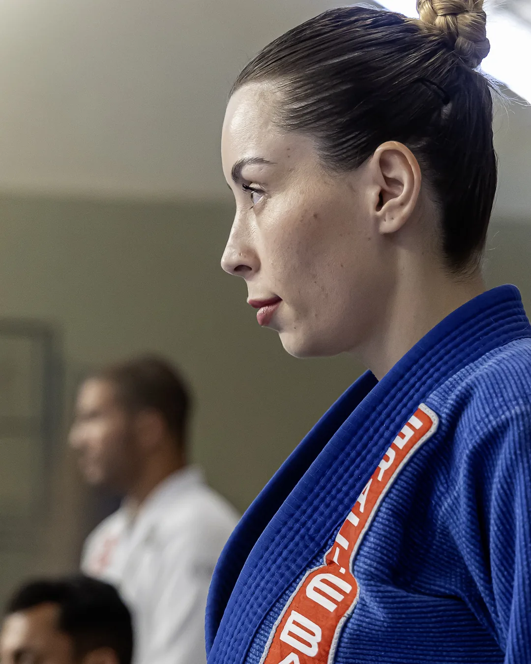 Atleta de kimono azul, de perfil, concentrada antes da luta