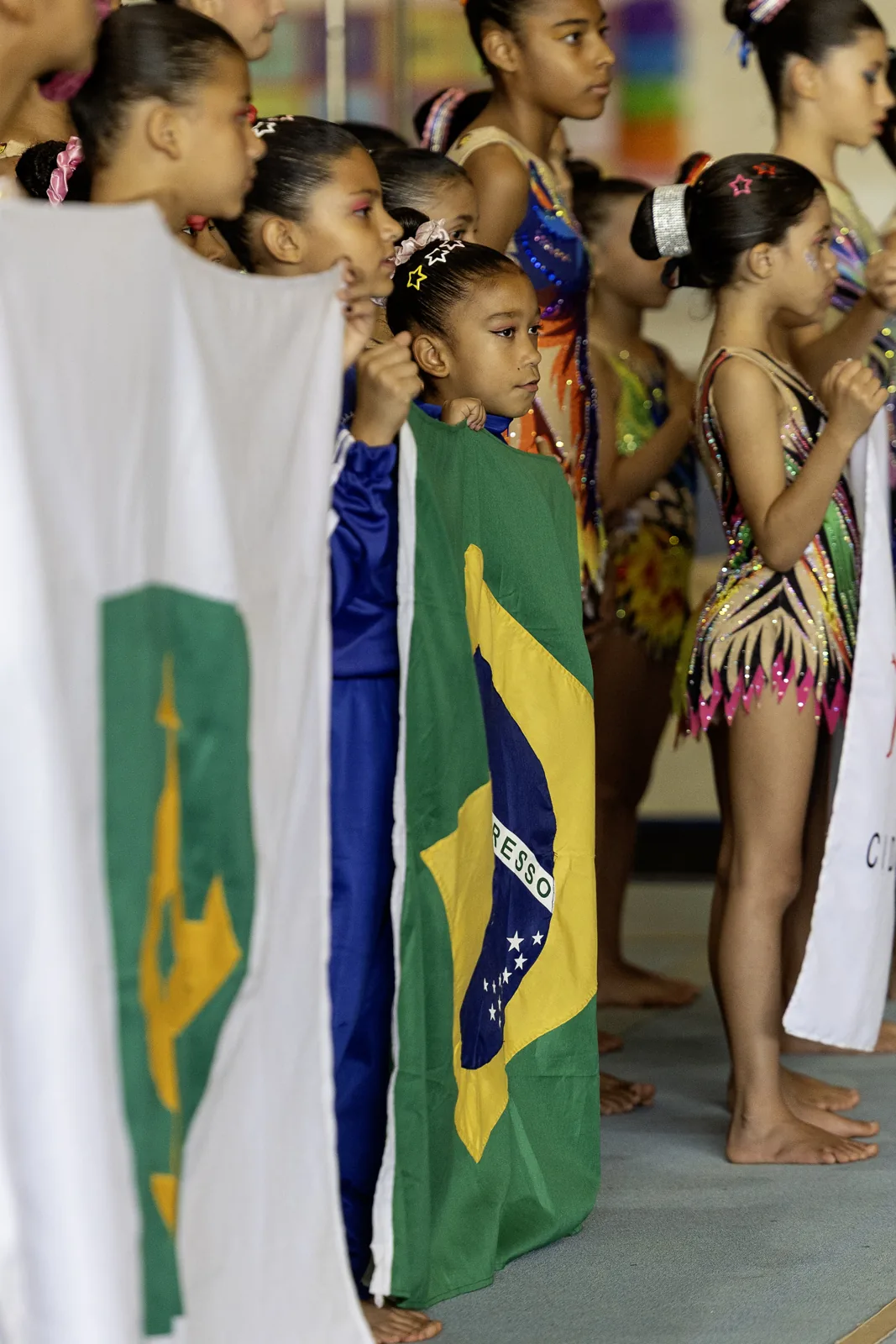 Ginastas em fila segurando as bandeiras do Brasil e do DF na cerimônia de abertura