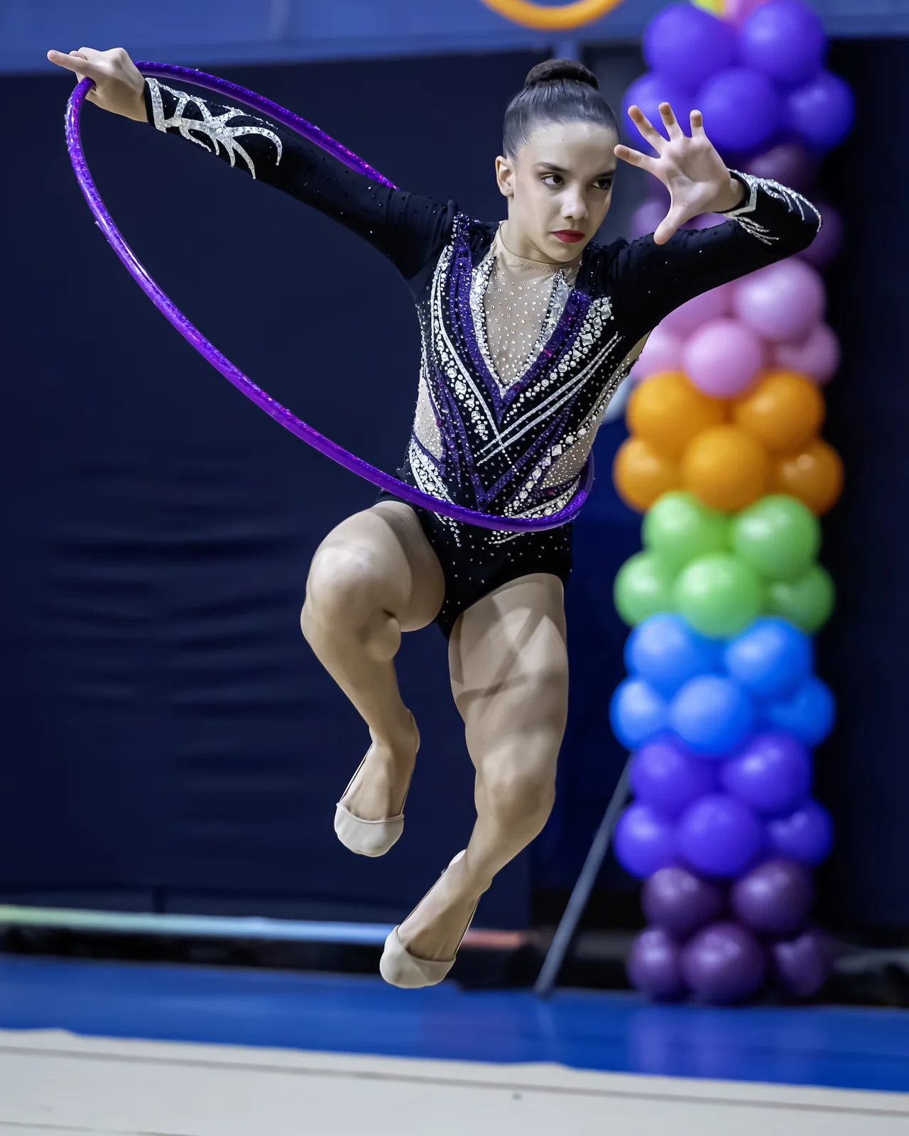 Ginasta em salto com o arco roxo girando à sua frente