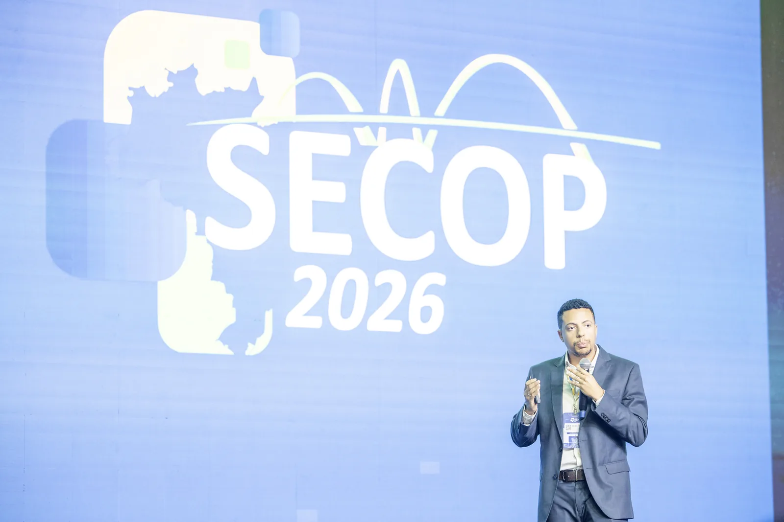 Palestrante fala diante do telão SECOP 2026