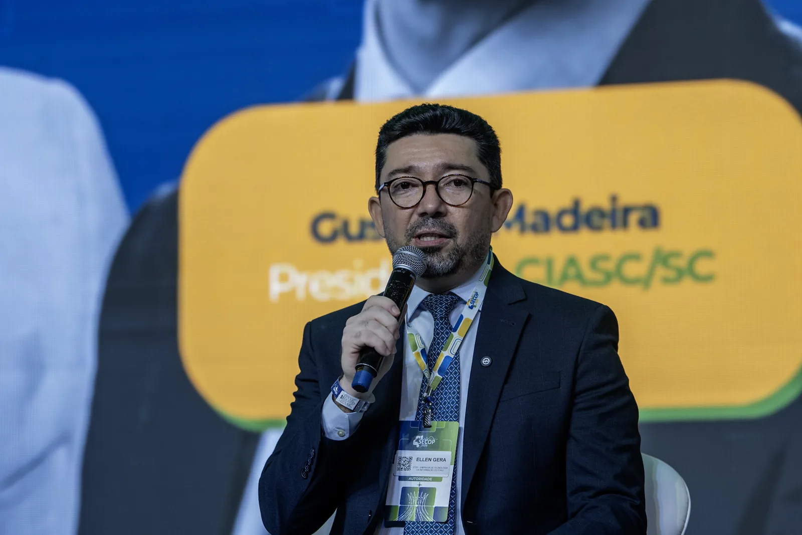 Dirigente fala ao microfone durante painel, em plano fechado