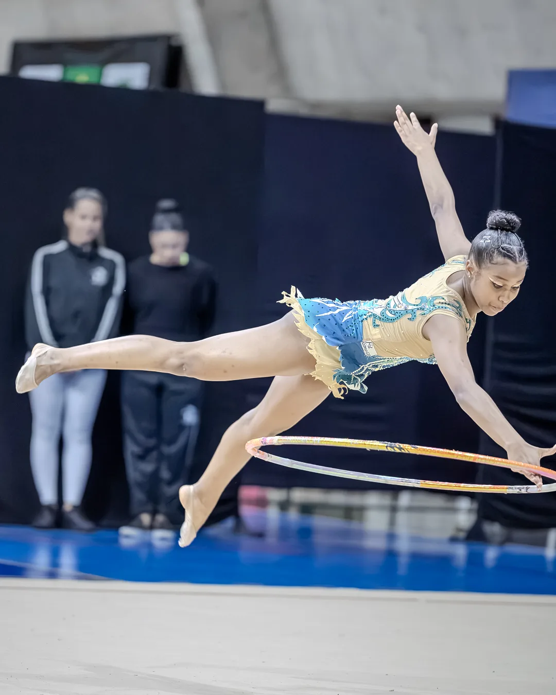 Ginasta em salto com as pernas estendidas e o arco