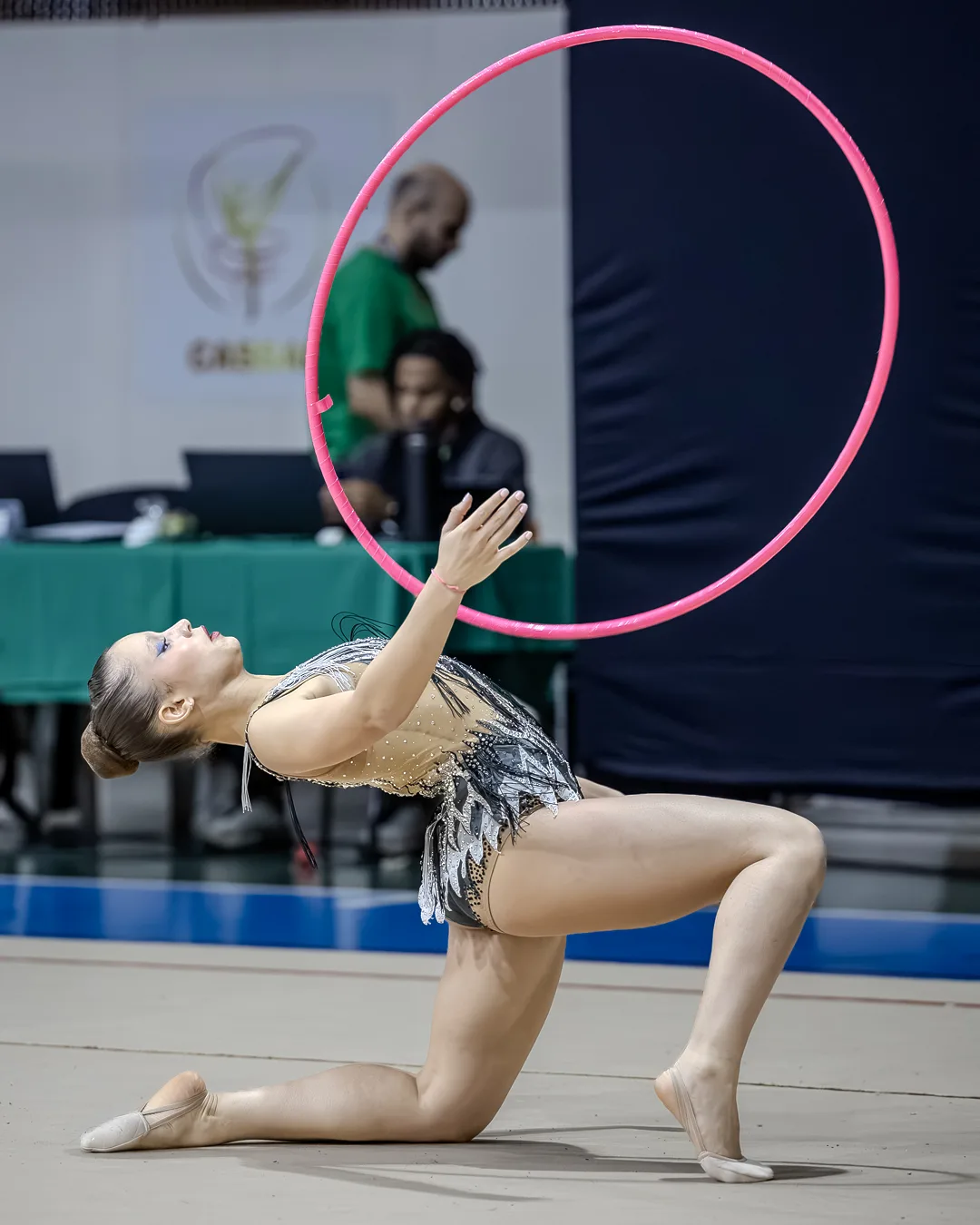 Ginasta em elemento de solo com o arco girando em primeiro plano