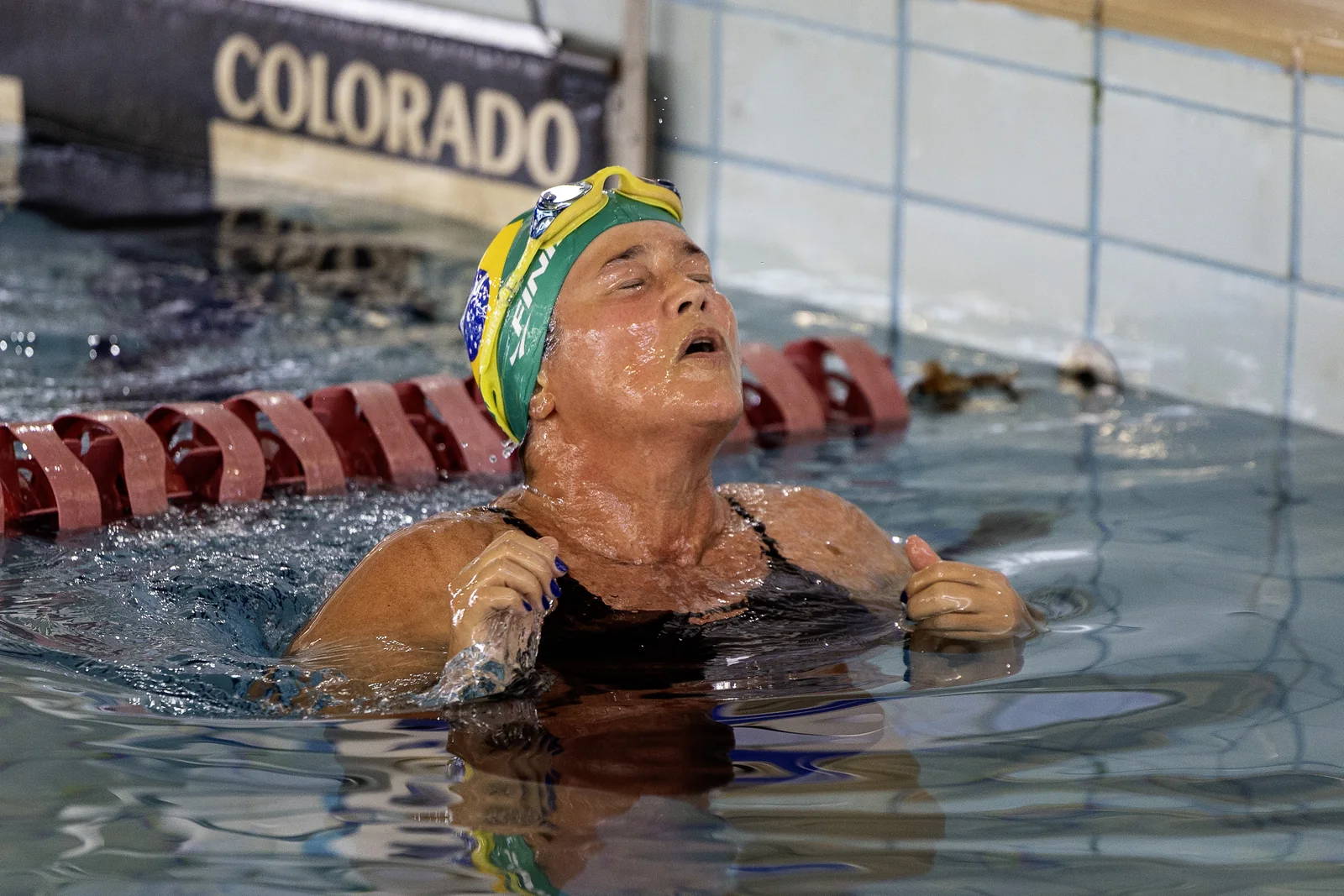 Nadadora master com touca do Brasil emergindo ao fim da prova