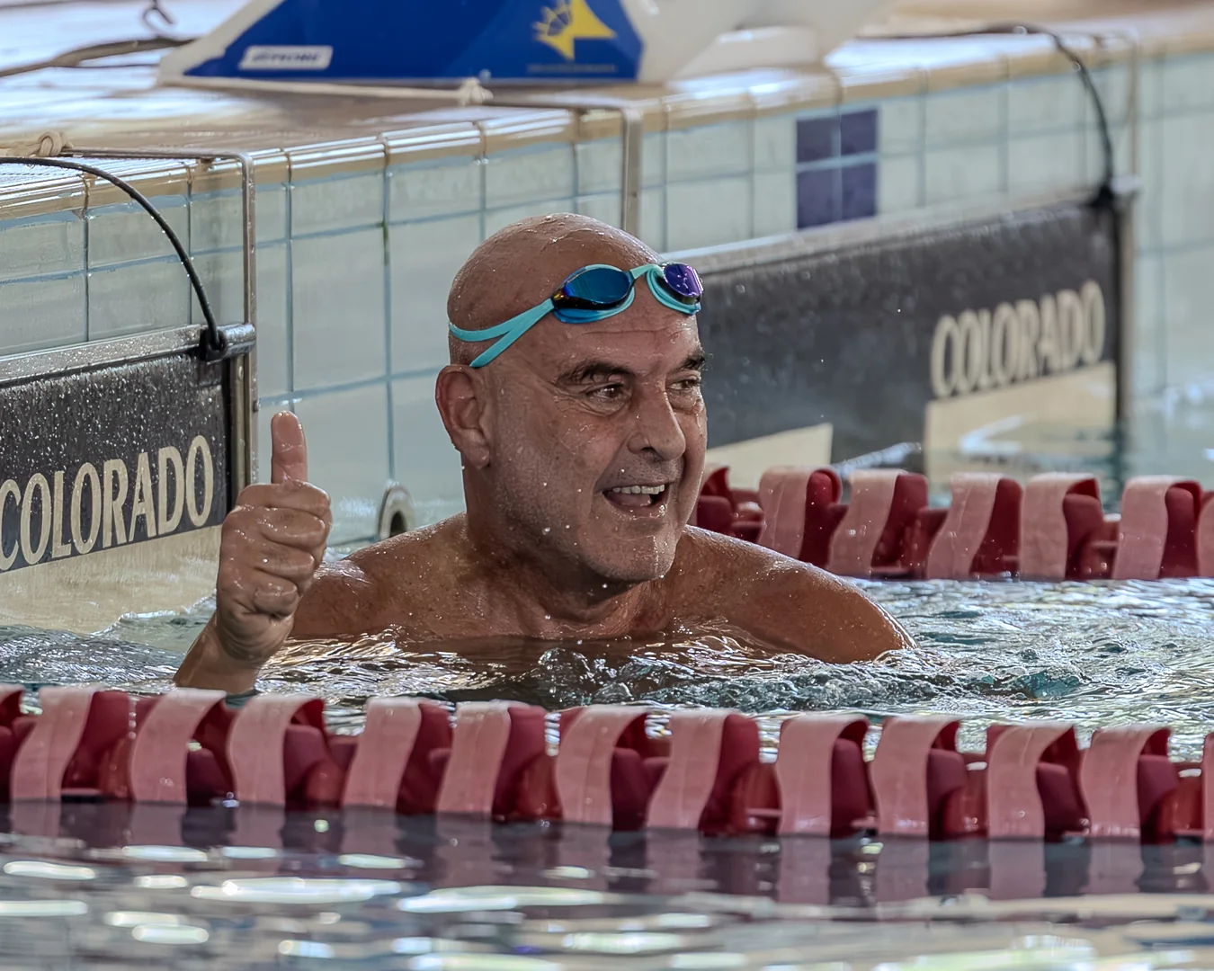 Nadador master sorrindo e levantando o polegar na borda da piscina